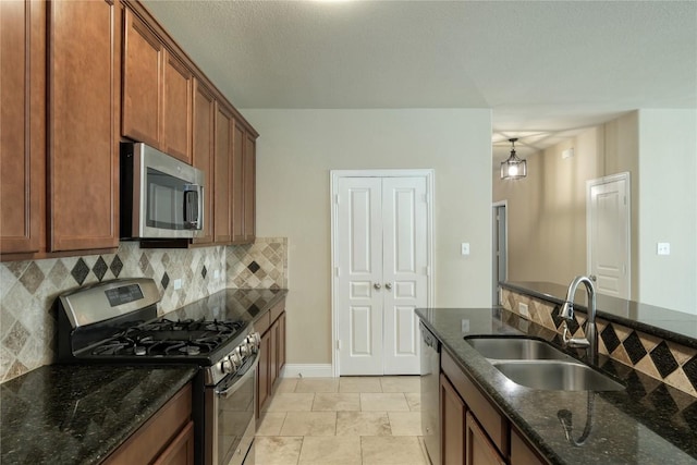 108 Tricia Ln, Hutto, TX 78634 - kitchen featuring appliances with stainless steel finishes, decorative backsplash, dark stone counters, and brown cabinetry