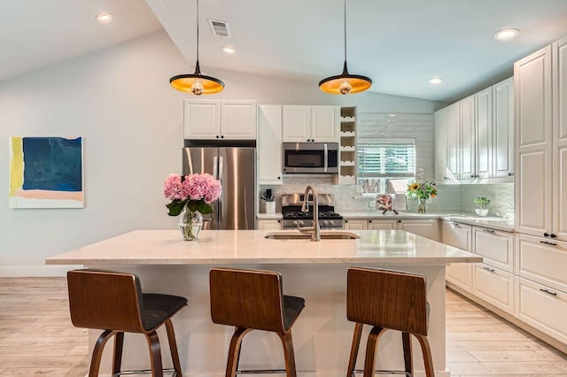 3013 Val Dr, Austin, TX 78723 - kitchen with stainless steel appliances, vaulted ceiling, light wood-style flooring, backsplash, and a breakfast bar area
