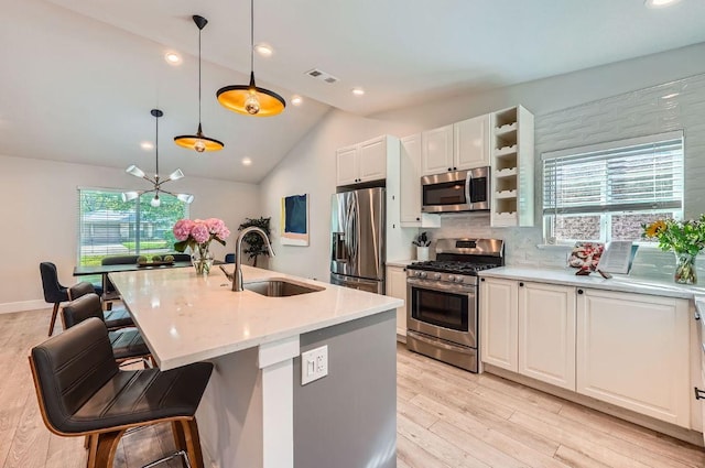 3013 Val Dr, Austin, TX 78723 - kitchen with appliances with stainless steel finishes, white cabinetry, vaulted ceiling, light stone counters, and decorative backsplash