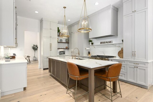 2314 Camino Del Verdes Pl, Round Rock, TX 78681 - kitchen featuring open shelves, tasteful backsplash, light wood-style floors, a kitchen island with sink, and recessed lighting