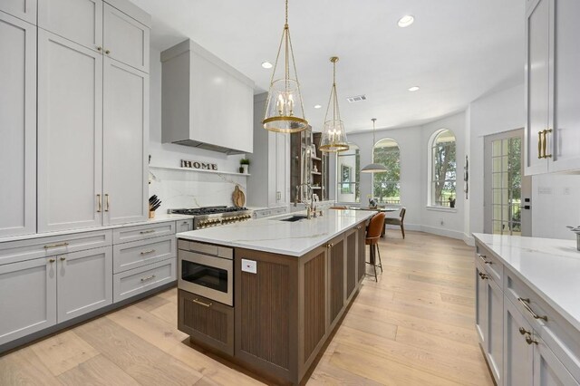 2314 Camino Del Verdes Pl, Round Rock, TX 78681 - kitchen featuring appliances with stainless steel finishes, recessed lighting, light wood finished floors, an island with sink, and light stone counters