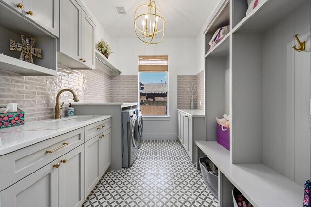 2314 Camino Del Verdes Pl, Round Rock, TX 78681 - laundry room featuring washing machine and dryer, cabinet space, light floors, and a chandelier