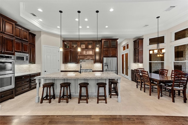 604 Flamingo Cv, Lakeway, TX 78734 - kitchen with appliances with stainless steel finishes, a spacious island, a breakfast bar, crown molding, and decorative backsplash