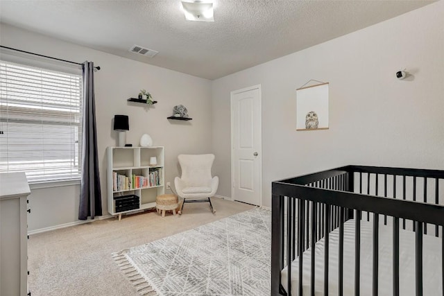 140 Housefinch Loop, Leander, TX 78641 - carpeted bedroom featuring multiple windows, a textured ceiling, and a crib