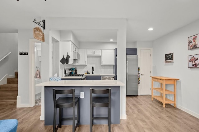 4800 Westgate Blvd Unit 103, Austin, TX 78745 - kitchen featuring stainless steel appliances, light countertops, a kitchen breakfast bar, light wood-style flooring, and recessed lighting