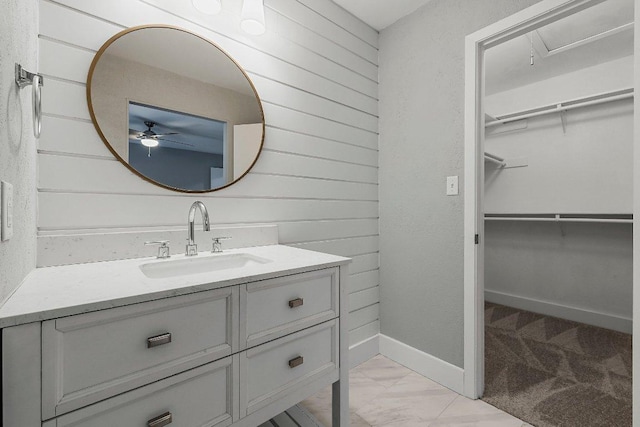 4904 Wing Rd, Austin, TX 78749 - bathroom featuring vanity, wooden walls, a spacious closet, a ceiling fan, and marble look tile flooring