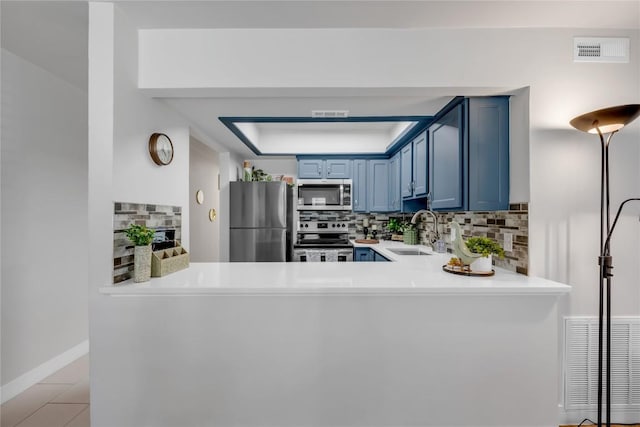 200 Free Rein Unit 5, Horseshoe Bay, TX 78657 - kitchen with stainless steel appliances, blue cabinets, a peninsula, backsplash, and light countertops
