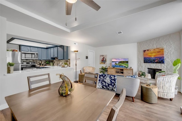 200 Free Rein Unit 5, Horseshoe Bay, TX 78657 - dining room with a ceiling fan, light wood finished floors, and a large fireplace