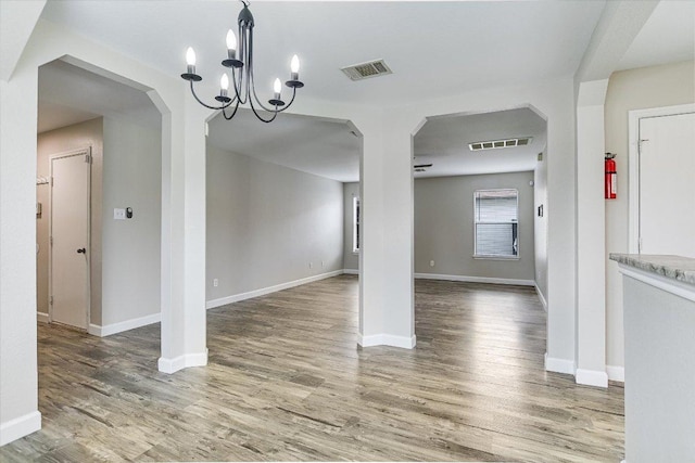 1000 Warbler Cv, Hutto, TX 78634 - unfurnished dining area with a chandelier, wood finished floors, and arched walkways