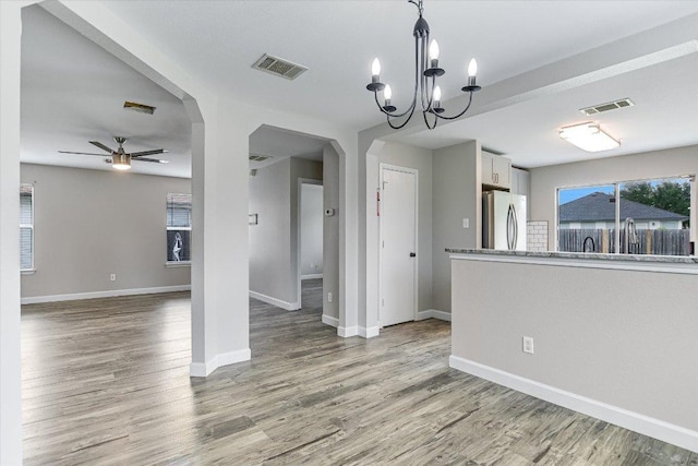 1000 Warbler Cv, Hutto, TX 78634 - empty room with arched walkways, ceiling fan, wood finished floors, and a chandelier