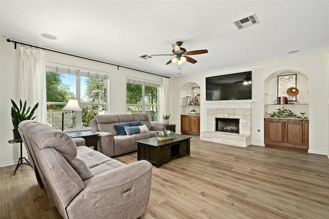 1903 Chula Vista Dr, Cedar Park, TX 78613 - living area with ceiling fan, light wood-type flooring, a stone fireplace, crown molding, and arched walkways