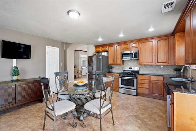700 Canyon Bend Rd, Pflugerville, TX 78660 - kitchen featuring stainless steel appliances, arched walkways, backsplash, brown cabinets, and recessed lighting