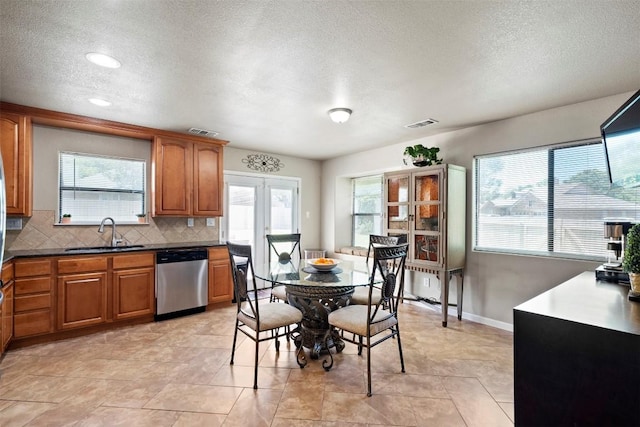 700 Canyon Bend Rd, Pflugerville, TX 78660 - kitchen featuring dishwasher, brown cabinets, a textured ceiling, backsplash, and plenty of natural light