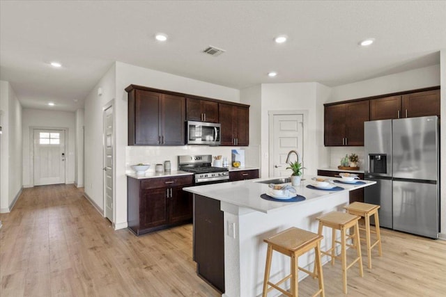 10708 Defender Trl, Austin, TX 78754 - kitchen featuring appliances with stainless steel finishes, a breakfast bar area, light countertops, a center island with sink, and light wood-style flooring
