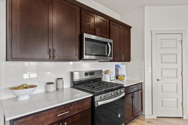 10708 Defender Trl, Austin, TX 78754 - kitchen with appliances with stainless steel finishes, tasteful backsplash, dark brown cabinets, and light countertops