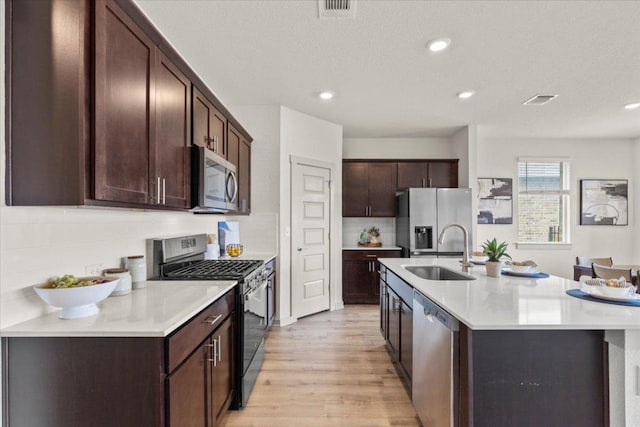 10708 Defender Trl, Austin, TX 78754 - kitchen featuring stainless steel appliances, light wood-style floors, dark brown cabinetry, tasteful backsplash, and light countertops