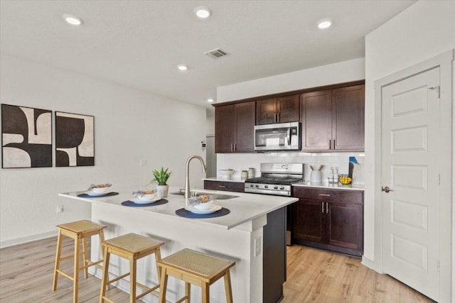 10708 Defender Trl, Austin, TX 78754 - kitchen featuring stainless steel appliances, a breakfast bar, light wood-style floors, light countertops, and recessed lighting