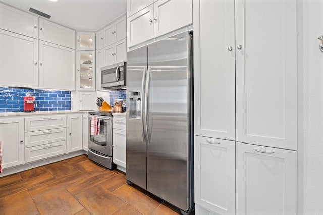 3702 Terrina St Unit 12, Austin, TX 78759 - kitchen featuring stainless steel appliances, light countertops, white cabinetry, glass insert cabinets, and backsplash