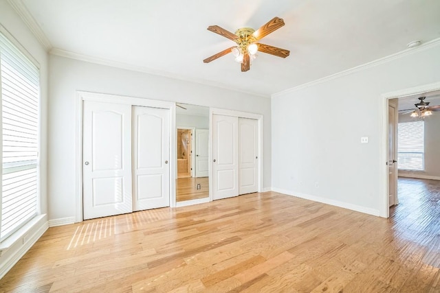 1213 Delsie Dr Unit A, Austin, TX 78734 - unfurnished bedroom featuring multiple windows, multiple closets, light wood-style flooring, ornamental molding, and a ceiling fan