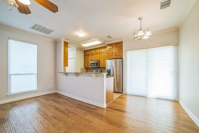 1213 Delsie Dr Unit A, Austin, TX 78734 - kitchen with stainless steel appliances, brown cabinets, ornamental molding, a peninsula, and a breakfast bar area