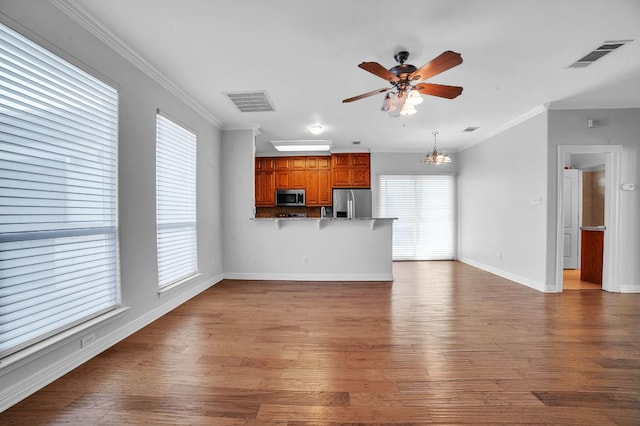 1213 Delsie Dr Unit A, Austin, TX 78734 - unfurnished living room featuring a ceiling fan, crown molding, wood finished floors, and a chandelier