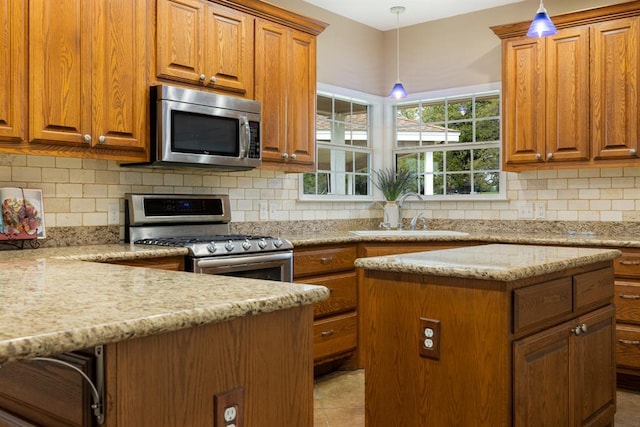 10565 N 77th Hwy, Lexington, TX 78947 - kitchen with stainless steel appliances, brown cabinetry, light stone countertops, backsplash, and pendant lighting