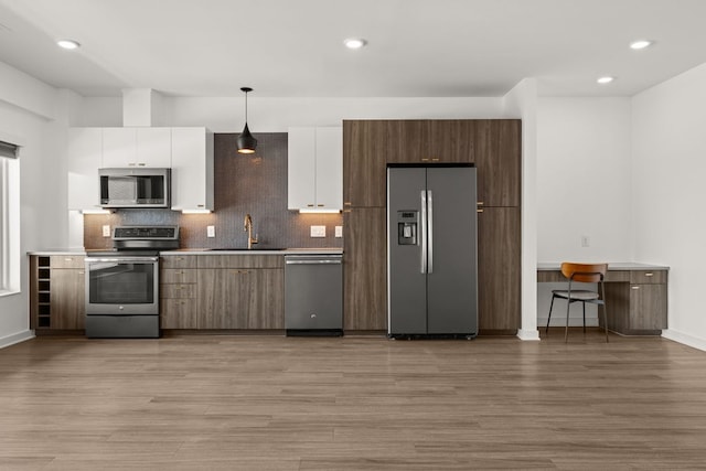 4361 S Congress Ave Unit 514, Austin, TX 78745 - kitchen featuring appliances with stainless steel finishes, light wood finished floors, white cabinets, tasteful backsplash, and recessed lighting