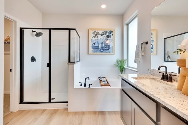 237 Hidalgo Ln, Elgin, TX 78621 - full bathroom with vanity, a stall shower, a garden tub, and wood finished floors