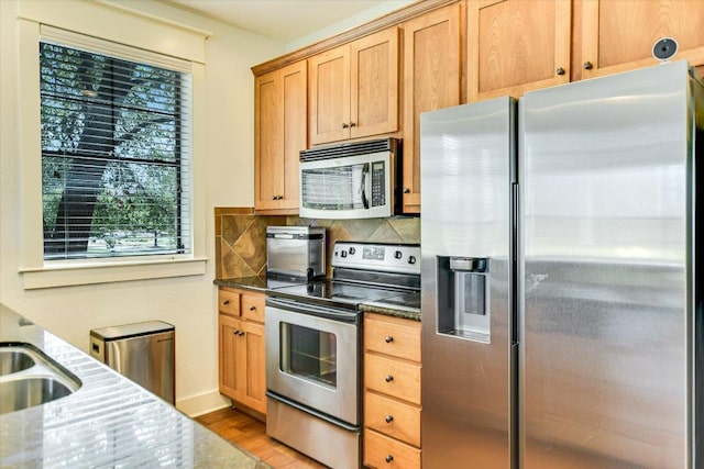 6608 Lantern View Dr Unit 102, Jonestown, TX 78645 - kitchen with stainless steel appliances, dark stone counters, light wood-style floors, and tasteful backsplash