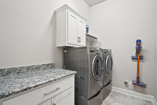 131 Katie Dr, Austin, TX 78737 - laundry room featuring washing machine and clothes dryer, cabinet space, and light marble finish flooring