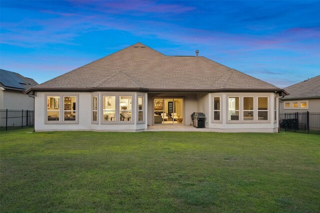 131 Katie Dr, Austin, TX 78737 - back of property at dusk with a shingled roof, a fenced backyard, stucco siding, and a patio area