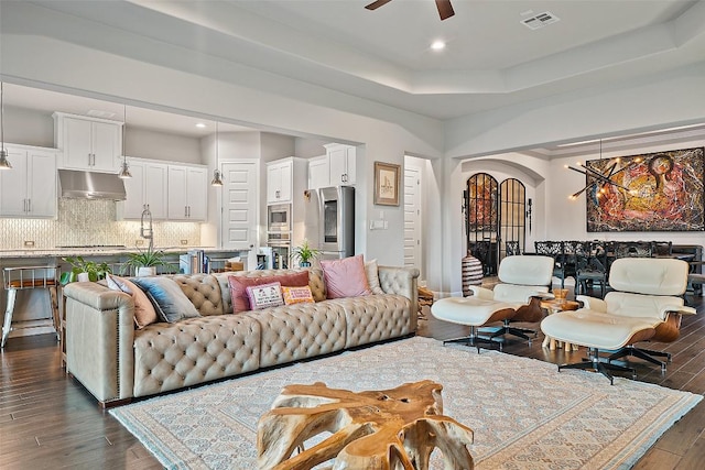 131 Katie Dr, Austin, TX 78737 - living room featuring dark wood-style flooring, arched walkways, a ceiling fan, recessed lighting, and a raised ceiling