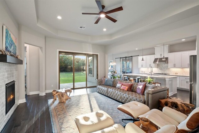 131 Katie Dr, Austin, TX 78737 - living area with a tray ceiling, a ceiling fan, dark wood finished floors, a fireplace, and recessed lighting