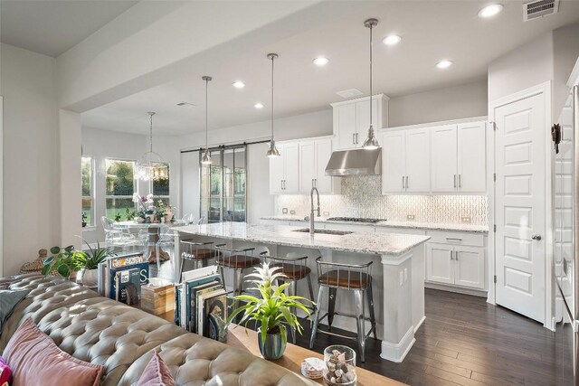 131 Katie Dr, Austin, TX 78737 - kitchen with under cabinet range hood, open floor plan, white cabinets, a breakfast bar, and backsplash