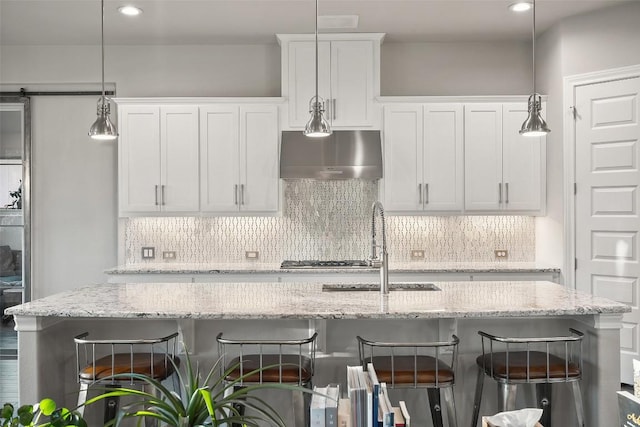 131 Katie Dr, Austin, TX 78737 - kitchen featuring wall chimney exhaust hood, a kitchen bar, white cabinets, backsplash, and pendant lighting