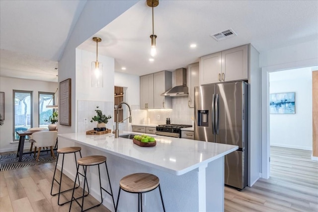 11202 Alhambra Dr, Austin, TX 78759 - kitchen featuring wall chimney exhaust hood, appliances with stainless steel finishes, a breakfast bar, decorative backsplash, and light wood-type flooring