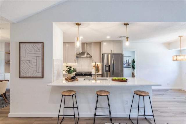 11202 Alhambra Dr, Austin, TX 78759 - kitchen featuring appliances with stainless steel finishes, wall chimney exhaust hood, a breakfast bar area, a peninsula, and vaulted ceiling