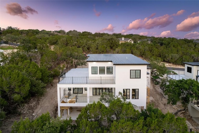 3206 Marshall Ave, Lago Vista, TX 78645 - rear view of house with a balcony, stucco siding, a view of trees, and a metal roof
