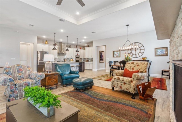 202 Iron Rail Ln, Georgetown, TX 78633 - living room featuring light wood-type flooring, a chandelier, ceiling fan, crown molding, and a tray ceiling