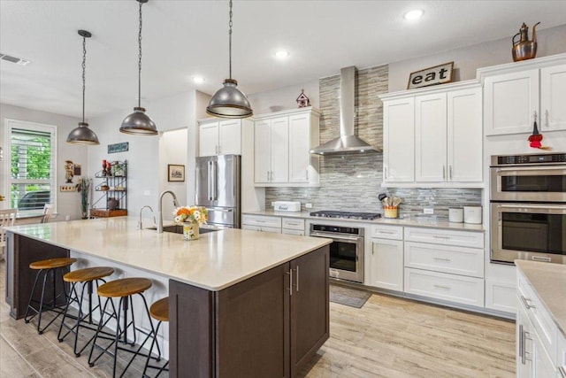 202 Iron Rail Ln, Georgetown, TX 78633 - kitchen with wall chimney exhaust hood, appliances with stainless steel finishes, light wood finished floors, decorative backsplash, and recessed lighting