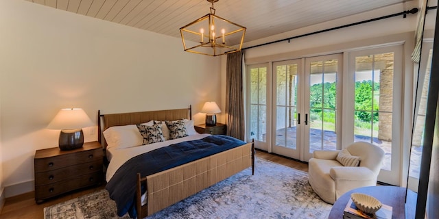 174 Putting Park Dr, Fredericksburg, TX 78624 - bedroom with french doors, access to outside, wood finished floors, and a chandelier