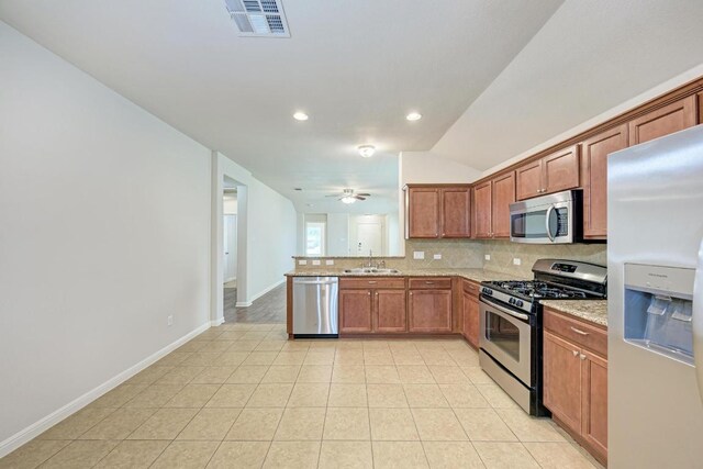 486 Nottingham Loop, Kyle, TX 78640 - kitchen with stainless steel appliances, decorative backsplash, a peninsula, brown cabinetry, and light stone counters
