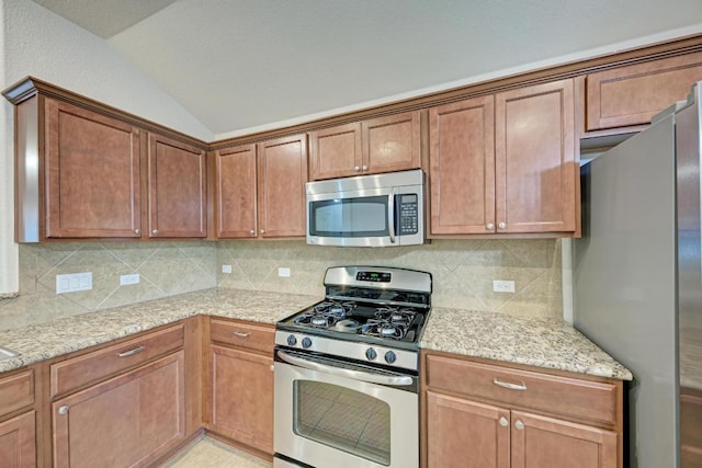 486 Nottingham Loop, Kyle, TX 78640 - kitchen with appliances with stainless steel finishes, vaulted ceiling, backsplash, light stone counters, and brown cabinets