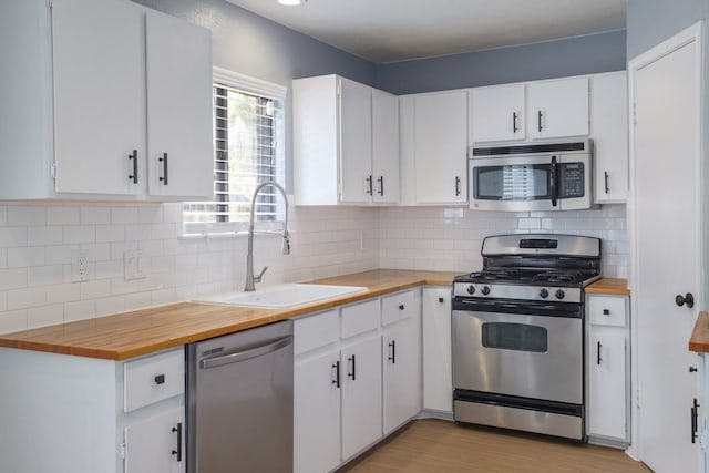 2616 Aylesbury Ln, Austin, TX 78745 - kitchen featuring appliances with stainless steel finishes, wood counters, and white cabinetry