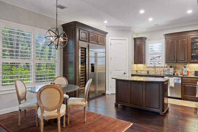 1036 Liberty Park Dr Unit 46, Austin, TX 78746 - kitchen with stainless steel appliances, dark brown cabinets, a center island, decorative backsplash, and ornamental molding