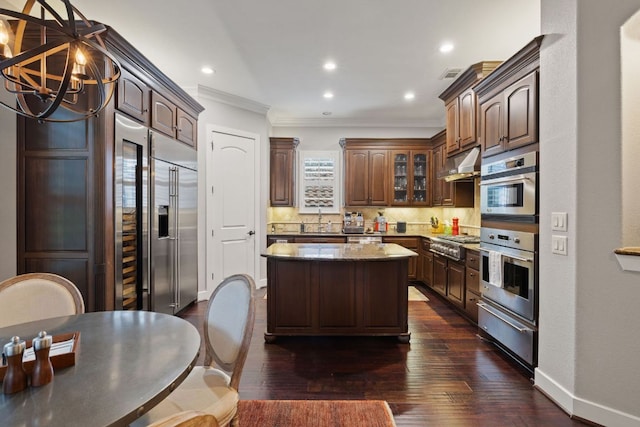 1036 Liberty Park Dr Unit 46, Austin, TX 78746 - kitchen featuring crown molding, under cabinet range hood, a warming drawer, a kitchen island, and tasteful backsplash