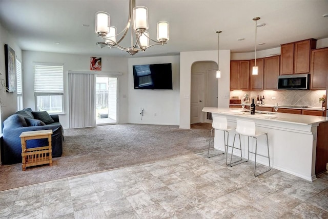 1928 Dragonfly Loop, Bastrop, TX 78602 - kitchen featuring stainless steel microwave, brown cabinets, light colored carpet, and pendant lighting