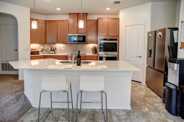 1928 Dragonfly Loop, Bastrop, TX 78602 - kitchen with appliances with stainless steel finishes, light countertops, backsplash, a center island with sink, and hanging light fixtures