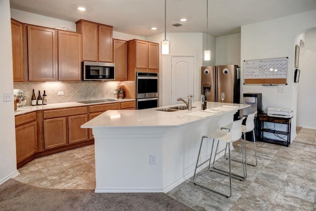 1928 Dragonfly Loop, Bastrop, TX 78602 - kitchen featuring stainless steel appliances, a kitchen island with sink, light countertops, hanging light fixtures, and a breakfast bar area
