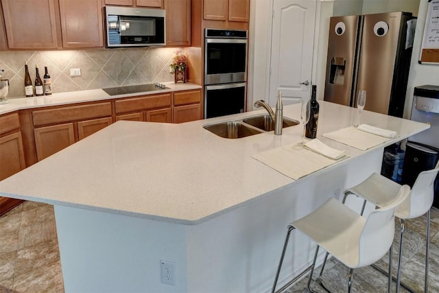 1928 Dragonfly Loop, Bastrop, TX 78602 - kitchen featuring stainless steel appliances, a kitchen breakfast bar, light countertops, backsplash, and a kitchen island with sink